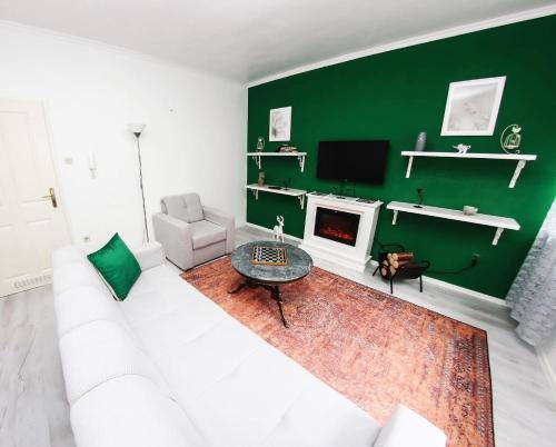 a living room with a white couch and a green wall at Forest Central Sarajevo in Sarajevo