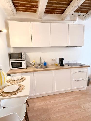 a white kitchen with white cabinets and a table at Provençal Studio - Vieil Antibes in Antibes