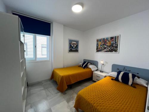 een slaapkamer met twee bedden en een raam bij CONIL CENTRO MERCURIO solo FAMILIAS in Conil de la Frontera