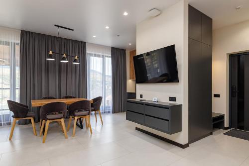 a dining room with a table and a flat screen tv at Chalet 348 in Palyanytsya