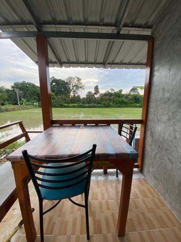 a wooden table and chairs on a porch with a window at สวรรค์บ้านนา คาเฟ่ ณ บ้านนา in Pakha