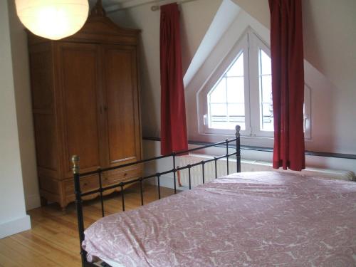 une chambre avec un lit avec des rideaux rouges et une fenêtre dans l'établissement le chaumont, à Stavelot