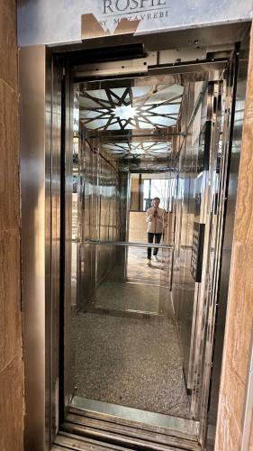 a person standing in front of a glass elevator at Sea Romantic Apartment in Gonio