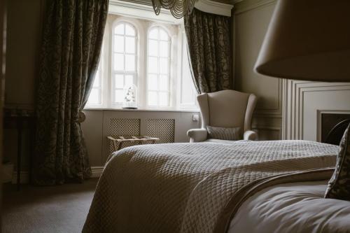 a bedroom with a bed and a chair and a window at Manor House Hotel in Bishop Auckland