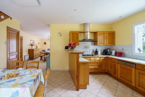 a kitchen with wooden cabinets and a table with a tablecloth at Ty Ma Breur - 5min de la Plage in Cléden-Cap-Sizun