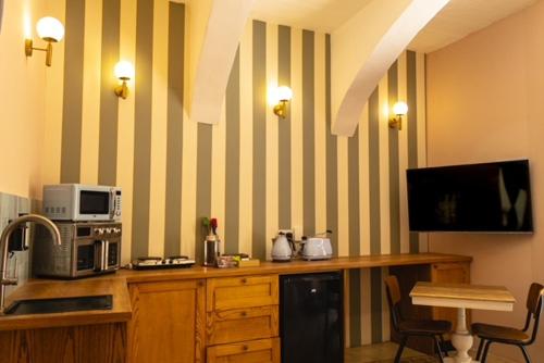 a kitchen with a counter with a microwave and a television at Mqabba Studio Flat by Talbot & Bons in Mqabba