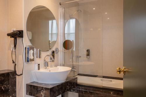 a bathroom with a sink and a shower and a mirror at Shanghai Hotel Holland in Delft