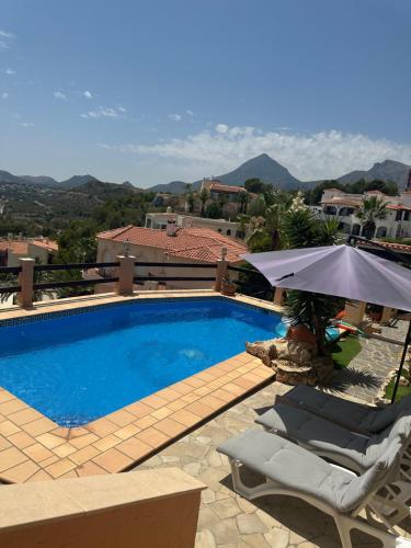 a swimming pool with two chairs and an umbrella at Cozy vacation home in L’Alfàs del Pi