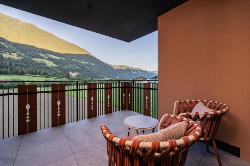 a balcony with two chairs and a table and mountains at Hotel Anewandter in Brunico
