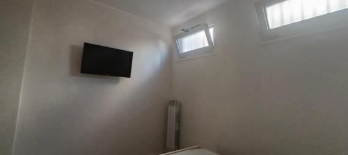 a bathroom with a toilet and a television on the wall at Esperia Maison B&b in Montesarchio