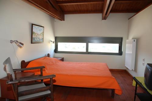 a bedroom with an orange bed and a window at Ktima Nikolaos in Arónion