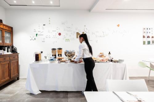 a woman standing in front of a table with food at Albergo La Rocca in Brisighella