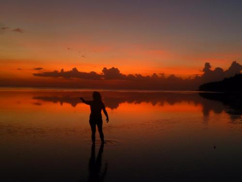 a woman standing on the beach at sunset at Villa Philibert in Riambel