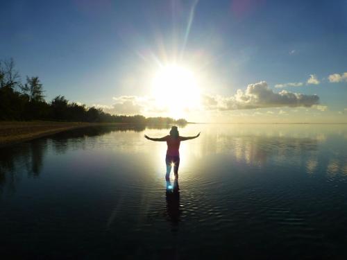 a woman walking in the water with the sun in the background at Villa Philibert in Riambel