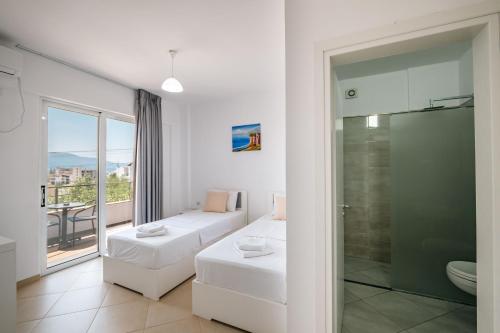 Una habitación blanca con un sofá y una ducha de cristal. en Sunshine Hotel, en Ksamil