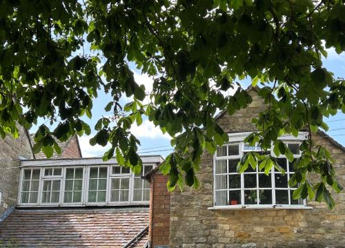 a brick house with white windows and a tree at Apartment above Samantha Dadd Art Studio - in the Cotswolds in Tewkesbury