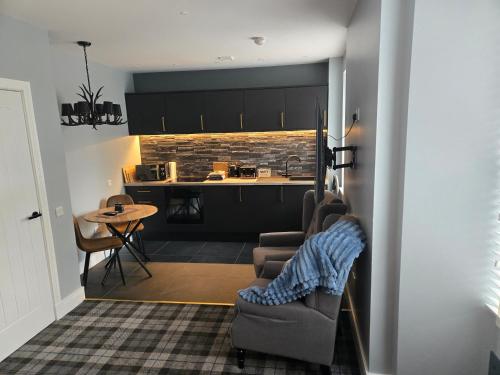 a living room with a couch and a kitchen at Ben Lomond Apartment in Tarbet