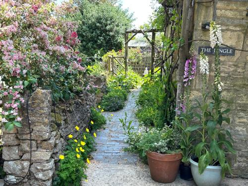 a garden with flowers and a stone path at Apartment above Samantha Dadd Art Studio - in the Cotswolds in Tewkesbury