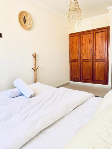 a bedroom with two white beds and a wooden cabinet at Waveside surf house in Tamraght Oufella