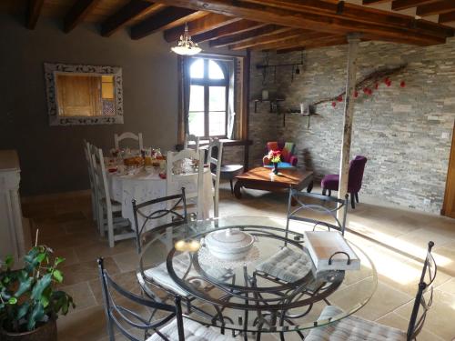 a dining room with a glass table and chairs at Le Moulin Chevillon in Cercy-la-Tour