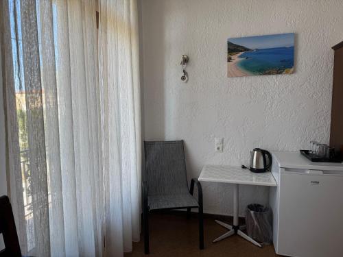 a room with a chair and a table and a window at Pythaïs Hotel in Pythagoreio