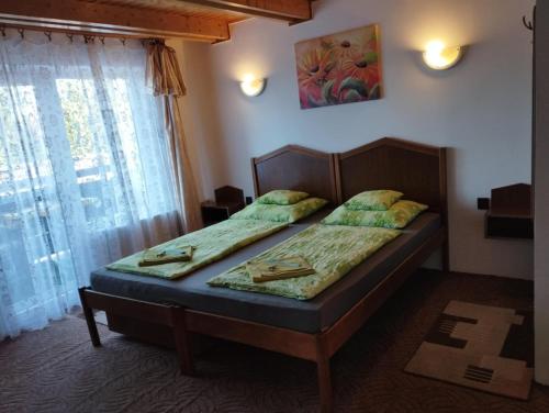 a bedroom with two beds in a room with a window at Fehérló Vendégház & Restaurant in Bük