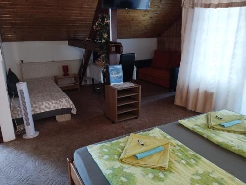 a room with two beds and a chair and a couch at Fehérló Vendégház & Restaurant in Bük