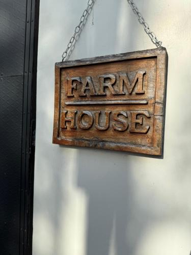 a sign that reads farm house hanging on a chain at Farm House in Kollam