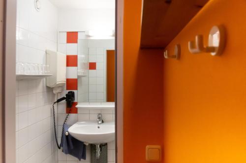 a bathroom with a white sink and a orange door at Schanzenstern Altona GmbH in Hamburg