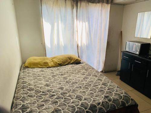 a bedroom with a bed with a pillow and a microwave at Kasi Roots Living in Soweto