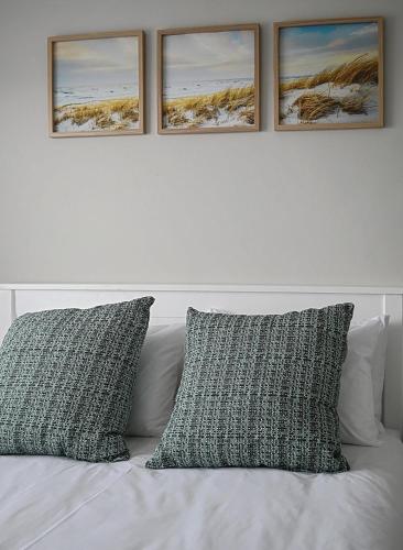a white bed with three pictures on the wall at Mountain and Oceanview at Blouberg in Cape Town