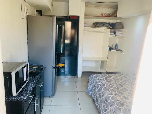 a small room with a bed and a refrigerator at Kasi Roots Living in Soweto