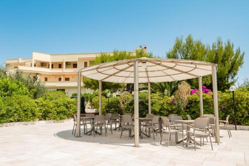 a group of tables and chairs under an umbrella at Hotel Sfinalicchio in Vieste