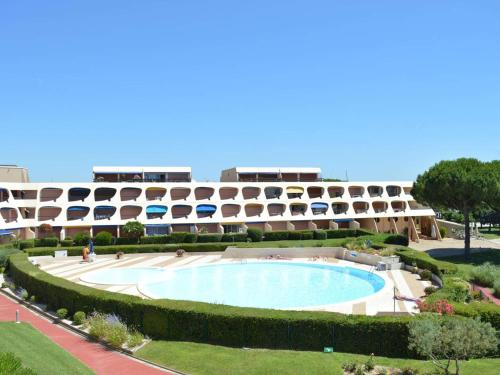 un complexe avec une grande piscine en face d'un bâtiment dans l'établissement Studio climatisé avec terrasse, piscine & parking, proche plage et port - Le Grau-du-Roi - FR-1-250-232, au Grau-du-Roi