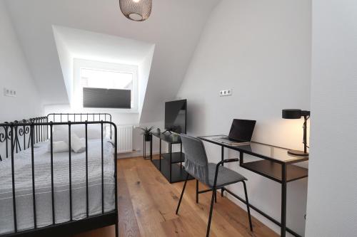 a bedroom with a bed and a desk with a laptop at helloYOU apartments I Wohntraum am Wasser I Zentral I Parkplatz I Nahewein in Bad Kreuznach