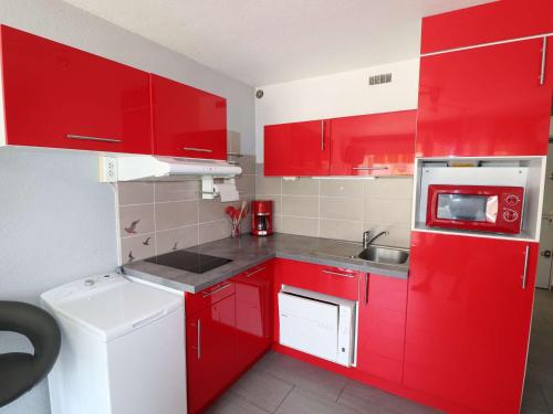 - une cuisine rouge avec un évier et des placards rouges dans l'établissement Studio climatisé proche mer avec terrasse, park privé et équipements modernes - FR-1-307-198, au Grau-du-Roi