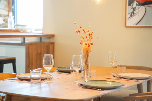 a wooden table with glasses and a vase with flowers at Les Granges du Hautacam in Artalens-Souin
