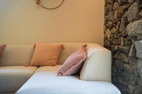 a couch with two pillows on it next to a stone wall at Les Granges du Hautacam in Artalens-Souin