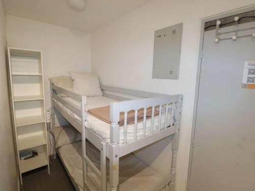 - un lit bébé blanc dans une chambre avec étagère dans l'établissement Studio climatisé proche mer avec terrasse, park privé et équipements modernes - FR-1-307-198, au Grau-du-Roi