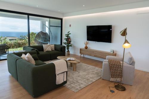 a living room with a couch and a tv at Auréa House - 4BR Azores Villa with Ocean View, BBQ & AC in Feteiras