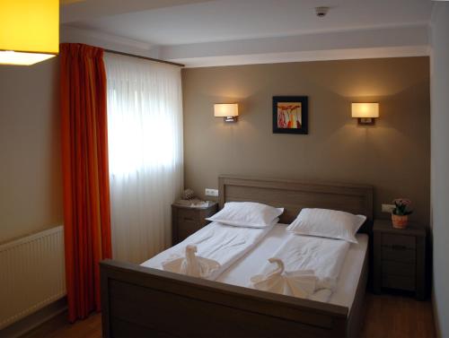 a bedroom with a bed with white sheets and pillows at Septimia Hotels & Spa Resort in Odorheiu Secuiesc