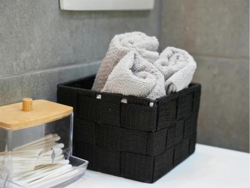 a black basket filled with towels on a bathroom counter at Duplex familiale 3 chambres, 3 salles de bains & jardin à Bruxelles by CYGO Gestion in Brussels
