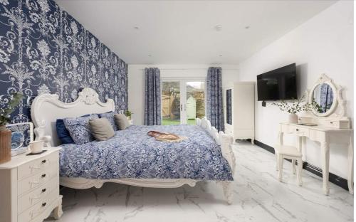 a blue and white bedroom with a bed and a tv at La Casita in Breage