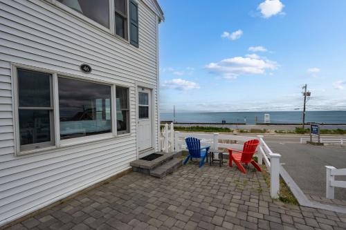 a patio with three chairs and a table next to a building at Oceanside Condos in Dennis Port