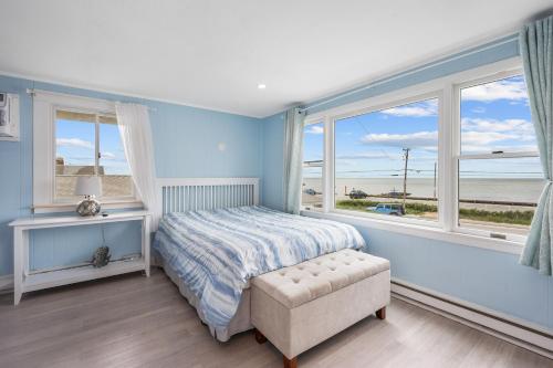 a bedroom with a bed and a chair and windows at Oceanside Condos in Dennis Port