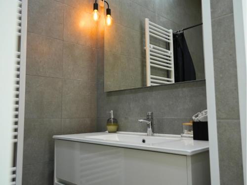 a bathroom with a white sink and a mirror at Duplex familiale 3 chambres, 3 salles de bains & jardin à Bruxelles by CYGO Gestion in Brussels