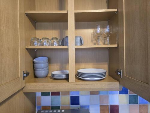 a cupboard with plates and glasses in it at Cosy 2-Bed House - Sleeps 5 Garden & Pet-Friendly in Leicester