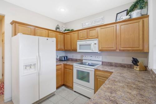 a kitchen with wooden cabinets and a white refrigerator at The Gathering Place - Minutes to 61-Acre Theme Park in Branson West