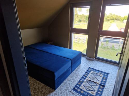 a bedroom with a blue bed and two windows at La Jura in Podlesice