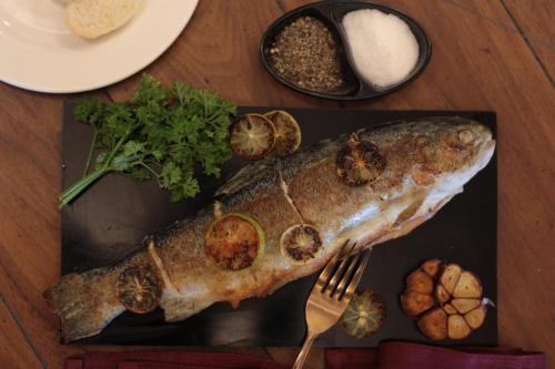 a fish on a plate with a fork and other foods at The Khyber Himalayan Resort & Spa in Gulmarg
